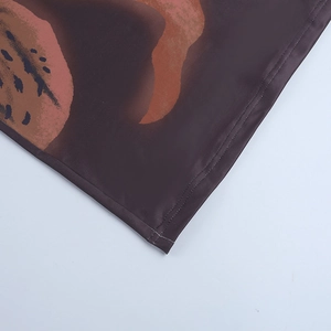 Close-up of double-needle stitching and orange spotted print on long-sleeve dress