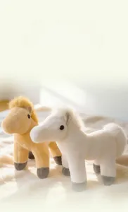 Gros plan de jolis poneys en peluche crème et blancs avec texture douce et yeux noirs