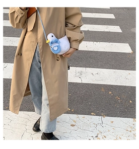 Detail of cute knitted duck crossbody bag with blue scarf on a walking model