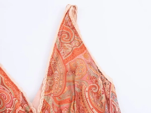 Dettaglio dello scollo con stampa paisley arancione e raffinato bordo in pizzo beige
