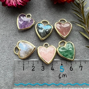 Natural heart crystal pendants with gold edges in various colors shown on a centimeter scale