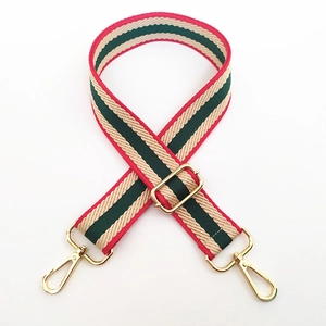 Detail of red and green striped woven bag strap with adjustable gold lobster buckles