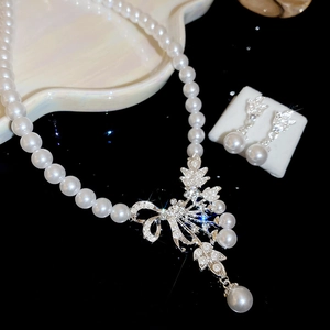 Detailed view of pearl necklace and bow earrings set with sparkling crystals