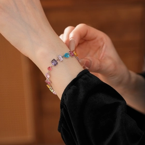 Detail of colorful oval zircon flower bracelet with purple and green gems on wrist