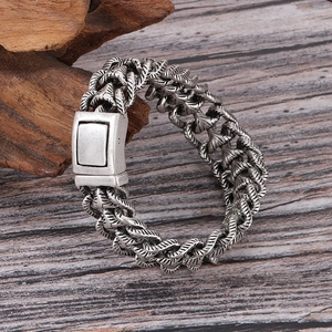Gros plan détaillé du bracelet gourmette rétro en argent sur fond en bois sombre