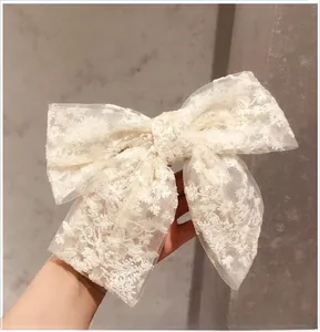 Close-up of a large cream lace bow hair clip featuring delicate floral embroidery detail