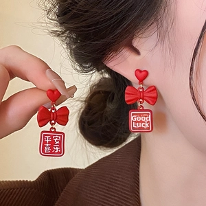 Detail of red festive tassel earrings with heart bow and blessing charms