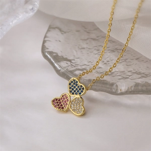 Macro d'un collier plaqué or 18K avec des pendentifs en cœur tricolores et zircons pavés