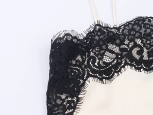 Detailed close-up of delicate eyelash lace trim and smooth satin fabric on a camisole top