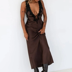 Détail d'une robe en satin marron avec col en V profond et bordure en dentelle noire
