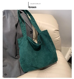 Detail view of deep green corduroy tote bag showing soft ribbed texture and long shoulder strap