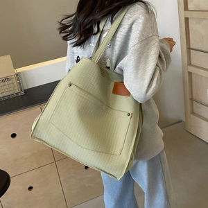 Detailed view of quilted light green canvas tote bag with front pocket and leather label