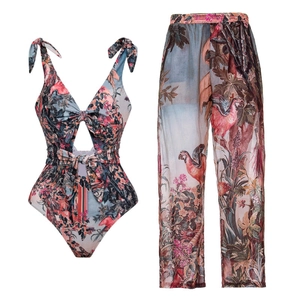 Detail of tropical leaf print on V-neck one-piece swimsuit and sheer beach trousers set