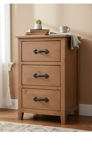 Detail of vintage black cast iron handle on a natural wood grain three-drawer cabinet