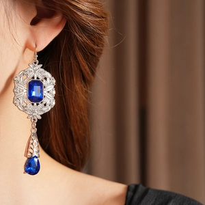 Detail of vintage teardrop earrings with blue gemstones and diamonds on model