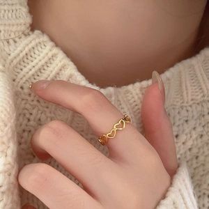 Detail of hollow heart-shaped gold ring worn with a warm knit sweater background