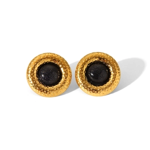 Gros plan de boucles d'oreilles rondes vintage en métal martelé doré et pierre bleue