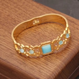 Vintage gold-plated stainless steel cat-eye bracelet with blue gemstones on a wood box