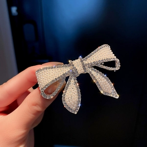 Gros plan sur une pince à cheveux nœud avec perles denses et strass brillants sur métal