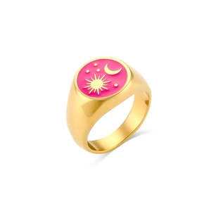 Dettaglio anello dorato con motivo sole e luna su smalto rosa e metallo lucido
