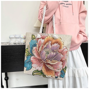 Detail of colorful peony floral embroidery on a beige woven canvas tote bag