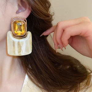 Close-up of vintage resin drop earring with marble pattern and golden gemstone on model