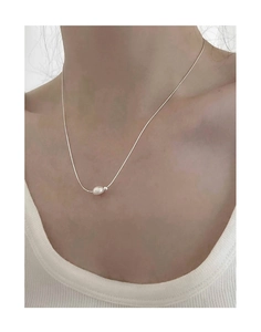 Close-up of a s925 silver necklace with a baroque freshwater pearl pendant on a model