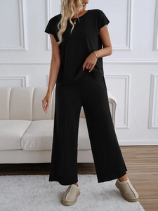 Detail eines minimalistischen schwarzen Stricksets mit Kurzarm-Oberteil und weiter Hose