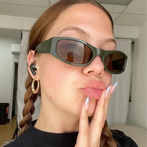 Retro oval sunglasses in dark green frame and tea lenses worn by a model