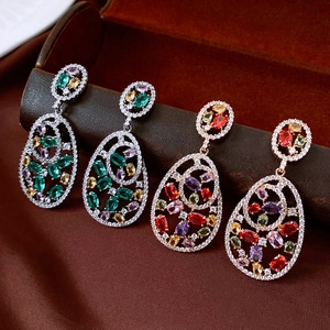 Detailed view of ornate hollow teardrop earrings with colorful zircon gemstones in velvet box