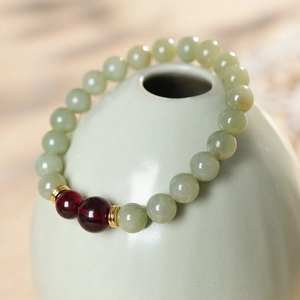 Macro detail of natural nephrite jade and agate beaded bracelet on a ceramic vase