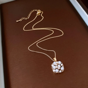 Detail of 18k gold plated necklace with square pearl and zircon pendant on dark background