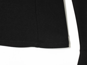 Close-up of the fine knit fabric texture and hem stitching on black flare pants