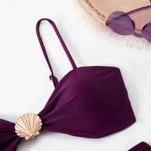 Detail of purple bikini top featuring a golden shell metal ornament and adjustable straps