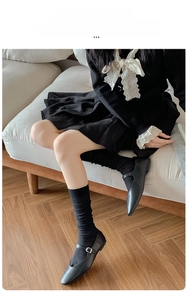 Detail of black ribbed calf socks with elastic fit paired with Mary Jane shoes