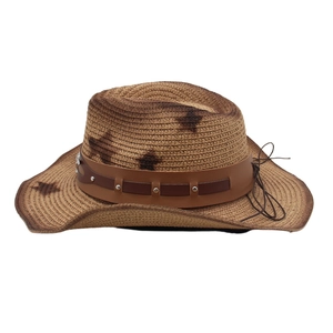 Detail of vintage straw cowboy hat featuring brown star patterns and studded leather band