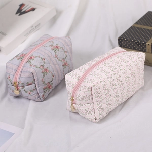 Macro detail of floral quilted makeup bag featuring gold zipper and cotton fabric texture