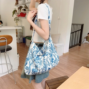 Detailed close-up of a blue floral cotton canvas shoulder bag in a cafe setting