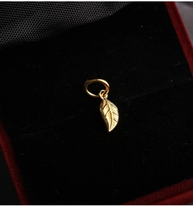 Macro shot of S925 silver leaf pendant with detailed gold finish veins on black velvet