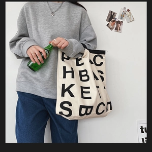 Detail of minimalist cream canvas tote bag with bold black PEACH BASKET typography