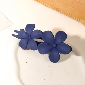 Detailed view of matte dark blue double flower hair clip on elegant white ceramic tray