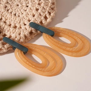 Retro amber resin layered oval earrings with dark green studs on woven fabric background