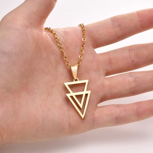 Detailed view of a hand holding a gold geometric triangle pendant necklace for men