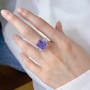 Macro shot of luxury ice-cut purple rectangular stone ring on finger with white fabric