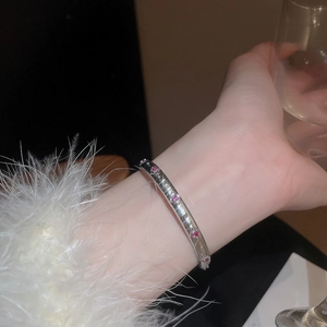 Detailaufnahme eines silbernen gebürsteten Armreifs besetzt mit rubinroten Zirkonsteinen