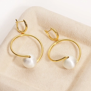 Detailed macro view of 18K gold-plated hoop earrings featuring a large white lustrous pearl
