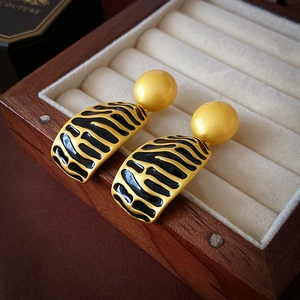 Vintage gold earrings with black enamel stripes in a wooden jewelry display box