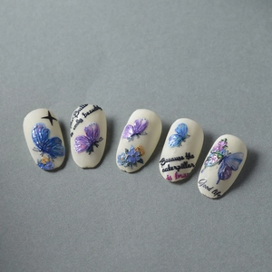 Detail of 3D embossed butterfly nail art with floral accents on creamy base