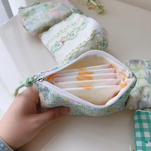 Détail d'une pochette en coton à fleurs montrant l'espace intérieur pour serviettes hygiéniques