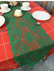 Detail of forest green lace table runner with intricate hollow floral patterns for Christmas